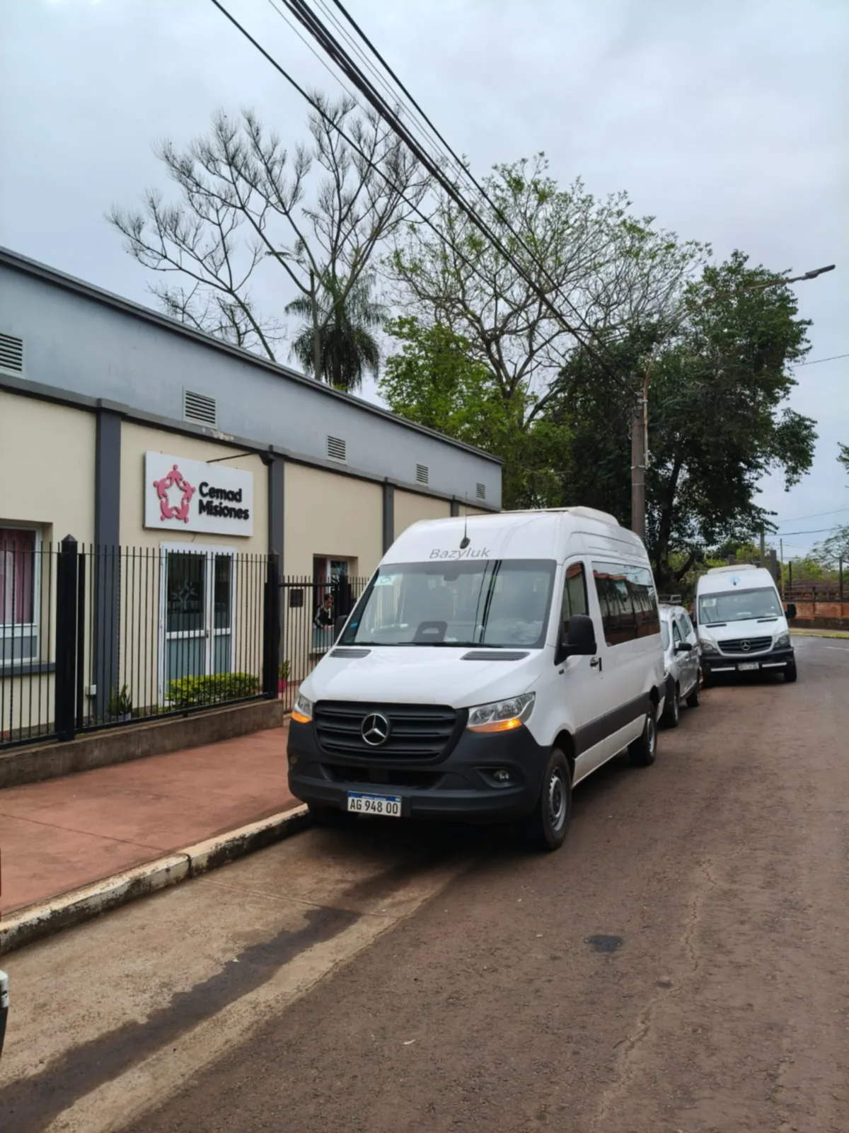 Dos minibuses de la institución estacionados frente a la sede, junto al cartel de CEMAD Misiones.